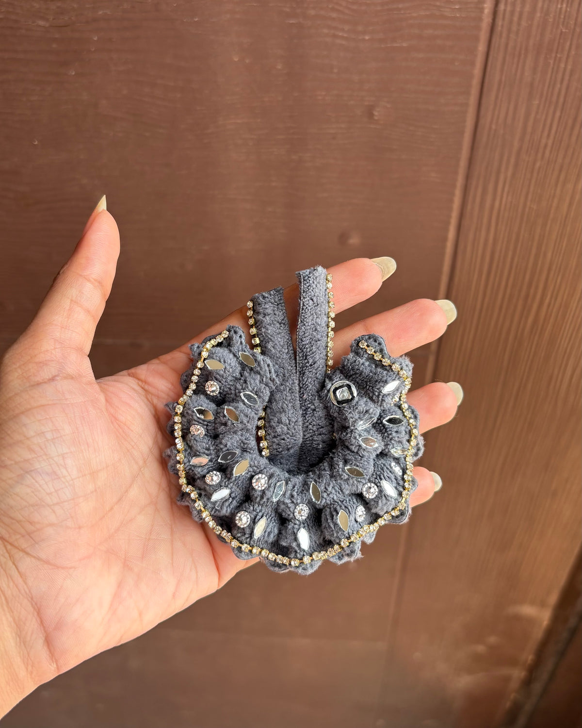Size 00 Laddu Gopal wearing a handmade grey dress with leaf-shaped mirror accents, sparkling stones and a golden border.